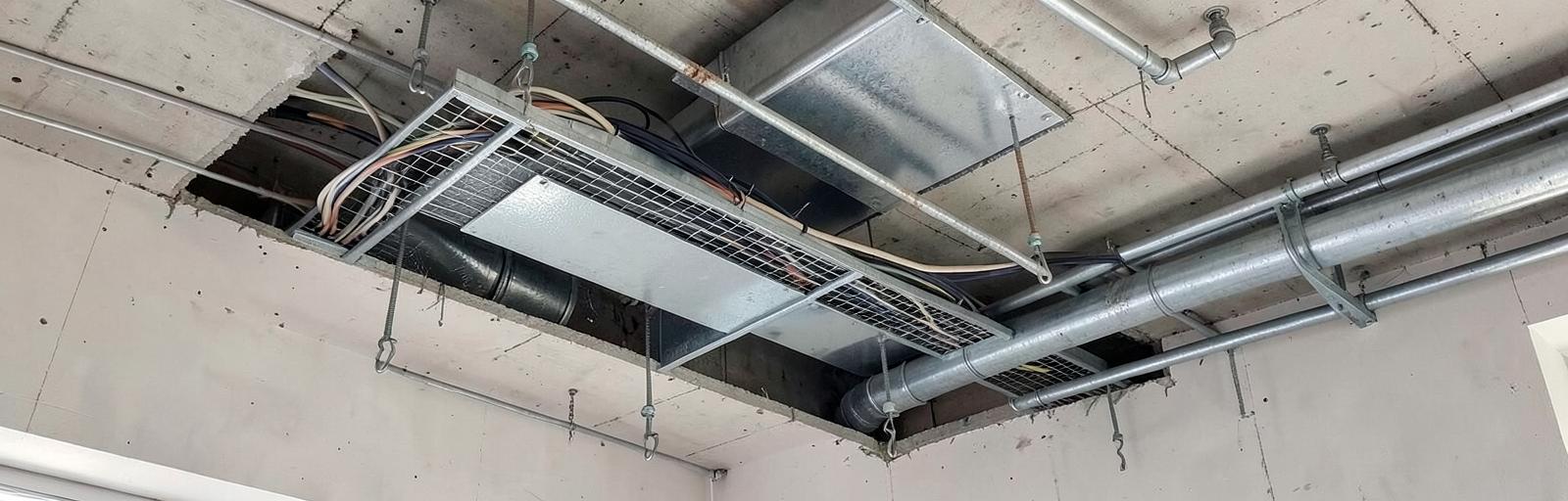 Tray kabel, jalur ducting, dan perpipaan yang berbagi ruang di atas plafon.